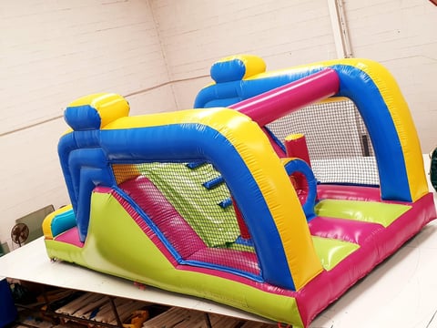 Colorful inflatable bounce house with blue, yellow, pink, and lime green panels displayed indoors