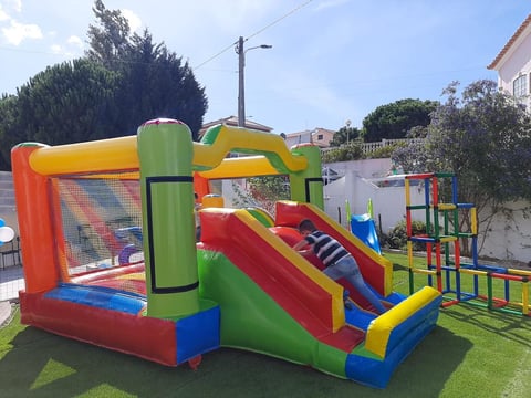 Colorful inflatable bounce house with slide and climbing structure in residential backyard on green lawn