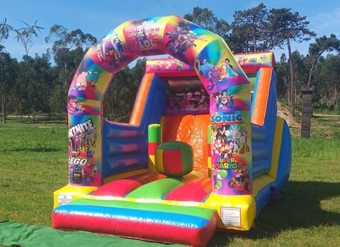 Colorful inflatable bounce house in a grassy outdoor area with trees in the background