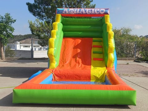 Colorful inflatable bounce house with orange slide and yellow accents in an outdoor paved area