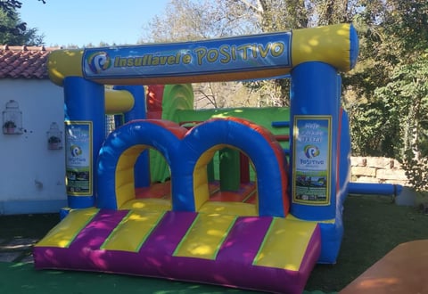 Colorful inflatable bounce house with blue frame, yellow and purple stripes, and arched entrance in outdoor setting