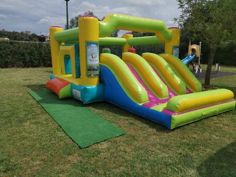 Colorful inflatable bounce house with slide in outdoor park setting on grass
